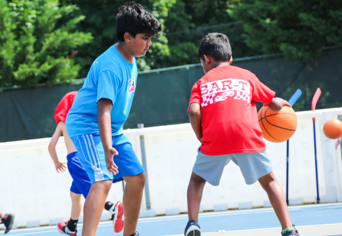 Campers playing a game of basketball outside on a court