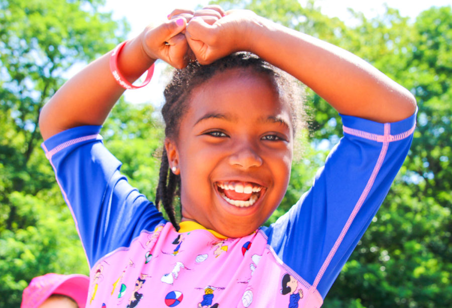 Camper smiling at the camera with hands above her head