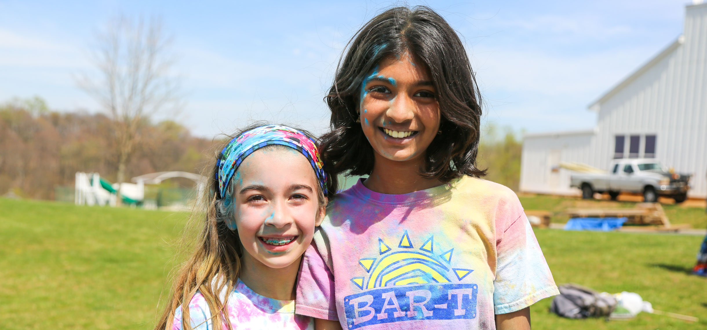 Two campers smiling for the photo after a color run covered in colored chalk