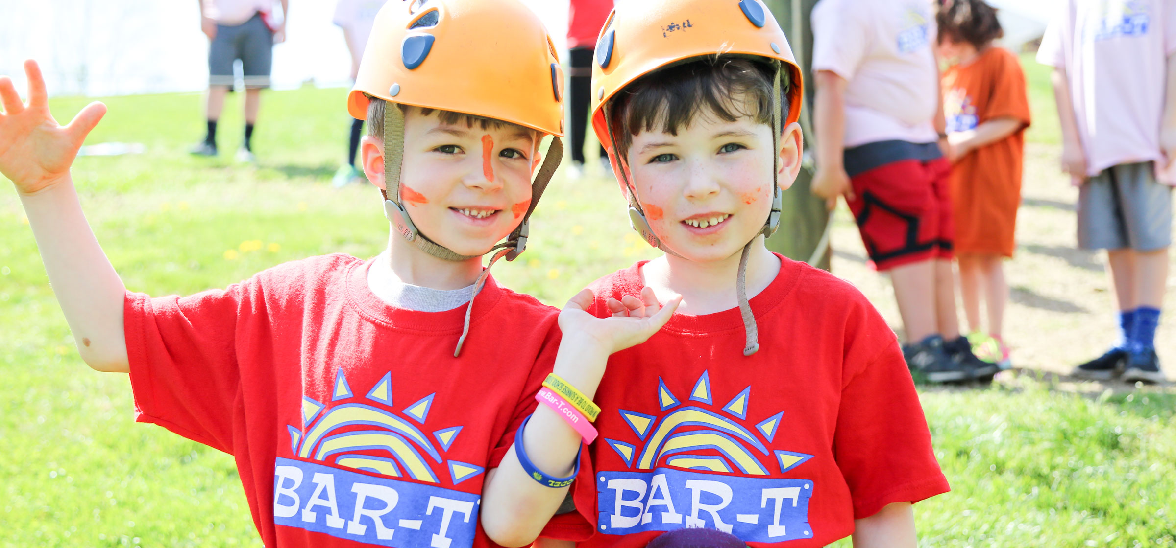 Two campers with helmets on ready to climb the rock wall