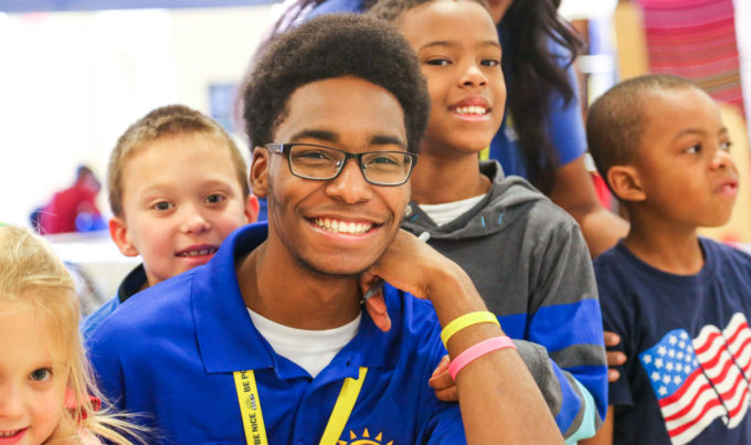 Staff member smiling with campers around him at a Bar-T school program